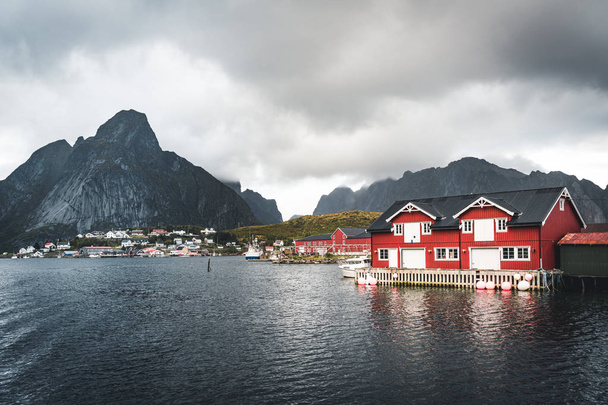 Landscape of fishing village Reine with the Reine Fjord during sunset with nice lights on mountain, blue sky and clouds. Lofoten, Norway. Photo taken in Norway. - Fotoğraf, Görsel