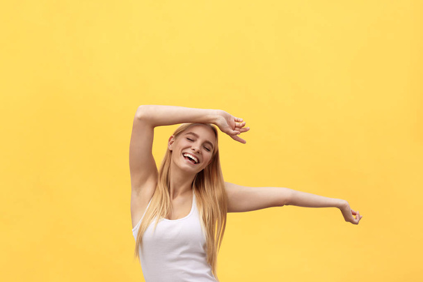 Young beautiful happy girl with hand in the air portrait isolated on yellow background. - Photo, image