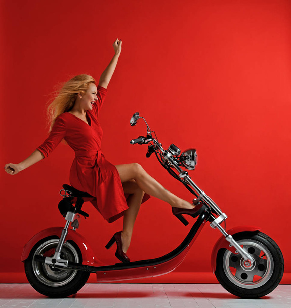 Nő lovagolni új elektromos autó motorkerékpár kerékpár robogó kerékpár piros ruha meglepett - Fotó, kép