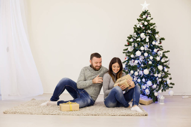 férj és feleség karácsonyfán ajándékot kínál az új évre - Fotó, kép