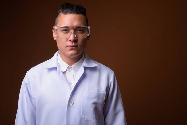 Mladý pohledný muž multietnické doktor proti hnědým pozadím - Fotografie, Obrázek