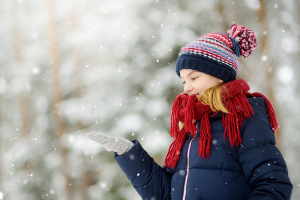 Suloinen pieni tyttö pitää hauskaa kauniissa talvipuistossa. Söpö lapsi leikkii lumessa. Talvi toimintaa lapsille
 - Valokuva, kuva