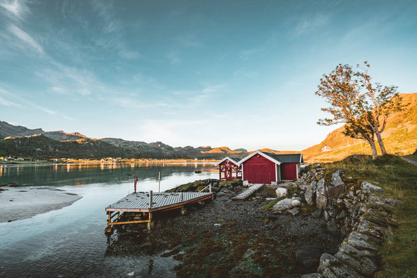 Traditional red fishin house in Bjoernsand near Reine in Lofoten, Norway with red rorbu houses. Sunset afternoon with clouds on a sandy beach. - Foto, imagen