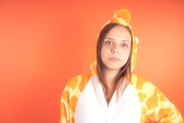 pajamas in the form of a giraffe. emotional portrait of a girl on an orange background. crazy and funny woman in a suit. animator for childrens parties - Fotoğraf, Görsel
