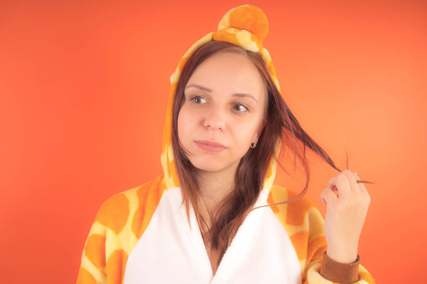 pajamas in the form of a giraffe. emotional portrait of a girl on an orange background. crazy and funny woman in a suit. animator for childrens parties - Foto, Imagem
