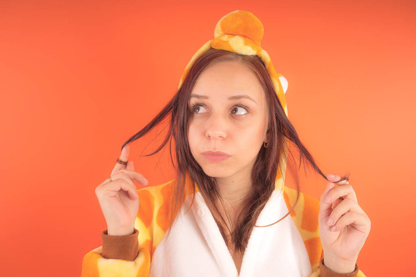 pajamas in the form of a giraffe. emotional portrait of a girl on an orange background. crazy and funny woman in a suit. animator for childrens parties - Photo, image