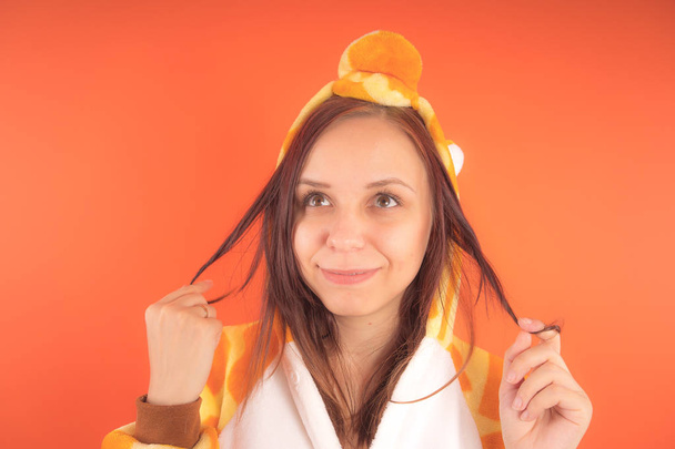 Pyjama on kirahvin muotoinen. emotionaalinen muotokuva tytöstä oranssilla taustalla. Hullu ja hauska nainen puvussa. animaattori lasten osapuolille
 - Valokuva, kuva