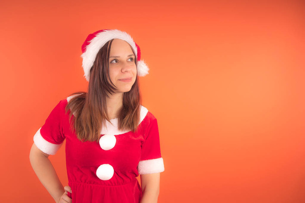 Portrait of a young girl dressed as Santa Claus on orange background. Happy New year and merry Christmas! - Фото, зображення