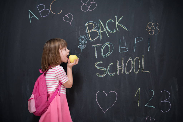 happy child with apple and back to school drawing in background on black chalkboard - Fotoğraf, Görsel
