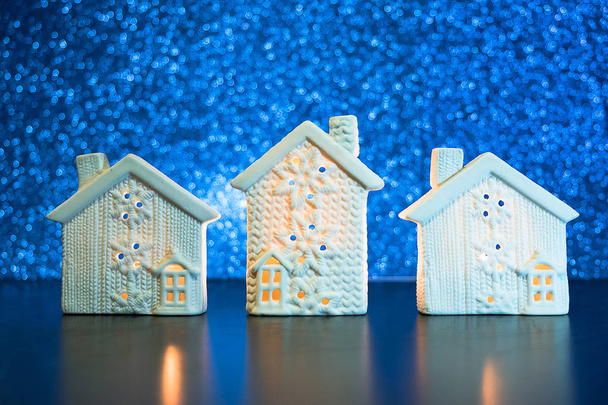 Nieuwjaar achtergrond met witte huisjes in de sneeuw. Lodges op blauwe wazig Glitter lichten achtergrond. hristmas huis concept. - Foto, afbeelding