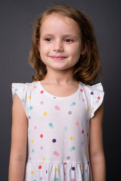 Милая молодая девушка с светлыми волосами на сером фоне - Фото, изображение