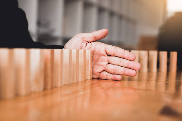 Fechar mão empresário impedindo bloco de madeira de cair na linha de dominó com conceito de risco
. - Foto, Imagem