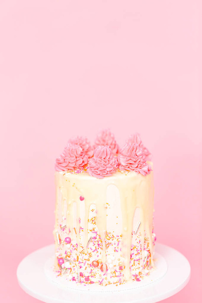 Pastel de crema de mantequilla rosa y blanca con chispas rosas y goteo de ganache de chocolate blanco
. - Foto, Imagen