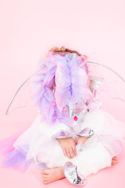 Retrato de una niña con traje de unicornio brillante sobre fondo rosa
. - Foto, imagen