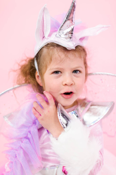 Portrait of a little girl in glitter unicorn costume on pink background. - Foto, imagen