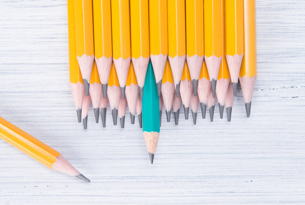 a row of yellow simple pencils on a light background and one green - Φωτογραφία, εικόνα