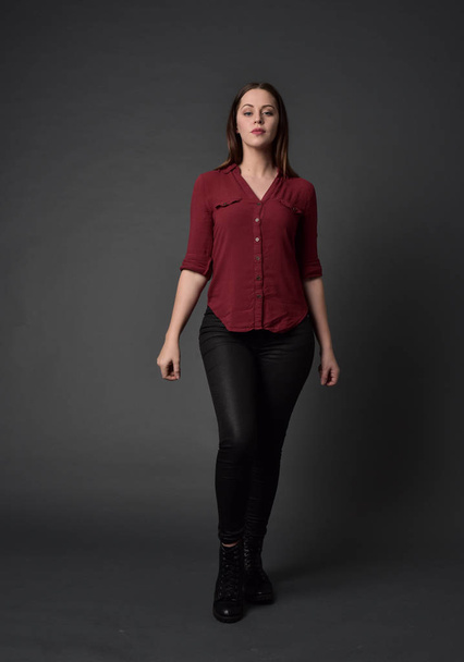 tam uzunlukta kırmızı gömlek ve deri pantolon giyen esmer kız portresi. gri studio arka plan üzerinde ayakta poz. - Fotoğraf, Görsel