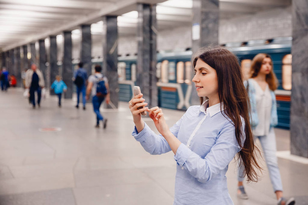 Młoda dziewczyna turystycznych rozmawia przez telefon, w metrze i uśmiechając się - Zdjęcie, obraz