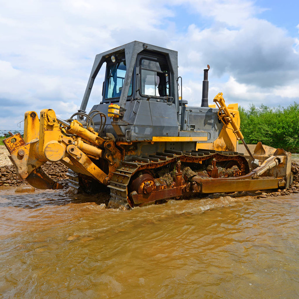 The bulldozer performs works in the tideway of mountain small river - Foto, Imagen