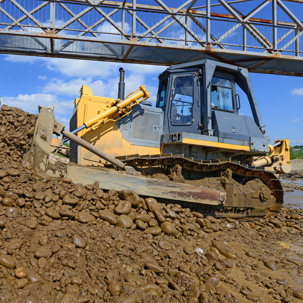 The bulldozer performs works in the tideway of mountain small river - 写真・画像