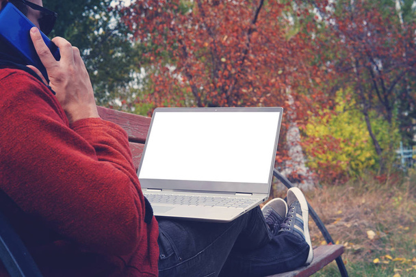 homem trabalhando ao ar livre sempre conectado com seu smartphone e seu laptop leal. jovem, freelancer trabalhando ao ar livre no outono Park
 - Foto, Imagem