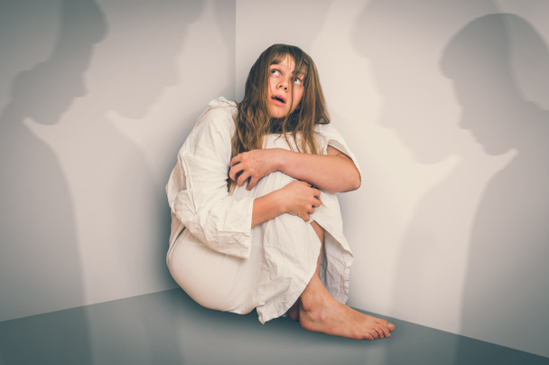 Mujer asustada con esquizofrenia sentada en la esquina de la habitación con sombras - alucinaciones y esquizofrenia concepto de enfermedad - estilo retro
 - Foto, imagen