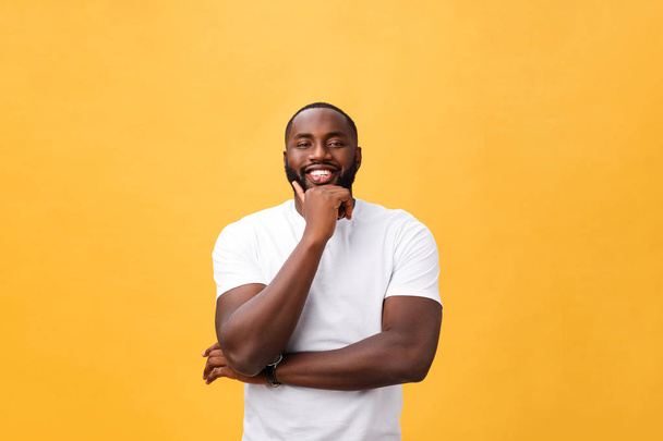 Πορτρέτο του ένα μοντέρνο νεαρός μαύρος άνδρας, χαμογελώντας με τα χέρια σταυρωμένα σε απομονωμένες κίτρινο φόντο - Φωτογραφία, εικόνα