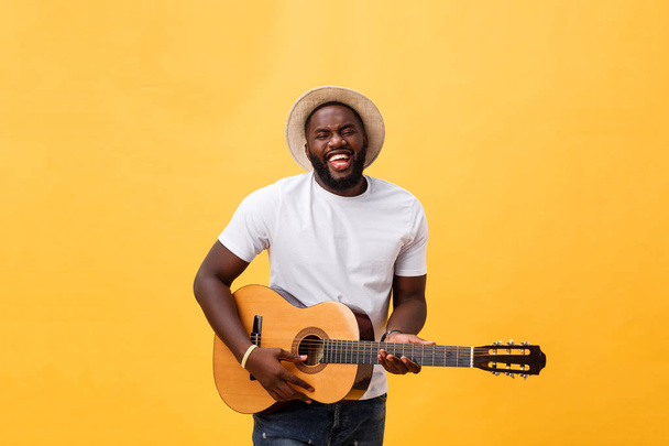 Komea afrikkalainen retro tyylistä kitaristi soittaa akustinen kitara eristetty keltaisella pohjalla
. - Valokuva, kuva