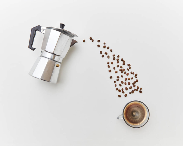 Italian coffee maker and fresh coffee beans coffee beans in the form of a drink stream on a white background with copy space. Concept of morning breakfast. Top view. - Photo, Image