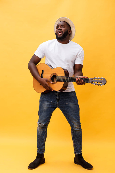 Ολόσωμο φωτογραφία συγκινημένο άνθρωπο καλλιτεχνική παίζοντας την κιθάρα του σε casual σουίτα. Απομονωμένα σε κίτρινο φόντο. - Φωτογραφία, εικόνα