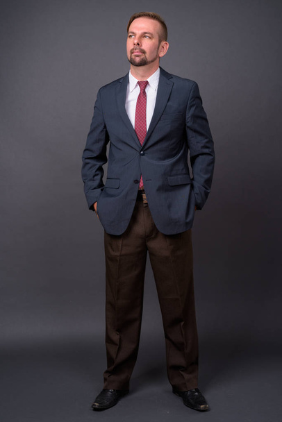 Блондин бородатий бізнесмен з гоатом на сірому фоні
 - Фото, зображення