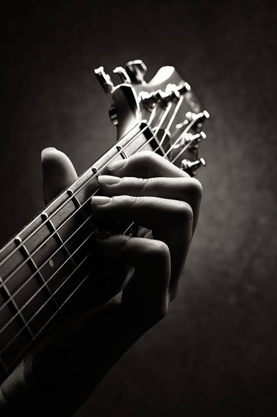 Mano de un guitarrista primer plano con solo el cuello y la cabeza de la guitarra en imagen
 - Foto, Imagen