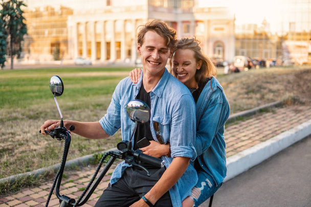 Preciosa pareja joven conduciendo bicicleta eléctrica durante el verano
 - Foto, Imagen