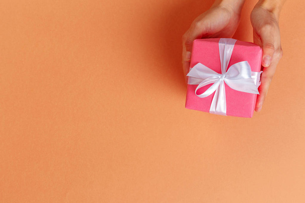 Woman holding gift box on color background - Photo, Image