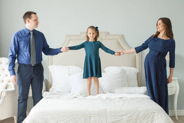 Perhe hyppii sängyllä. Äiti, isä, lapsi tytär
 - Valokuva, kuva