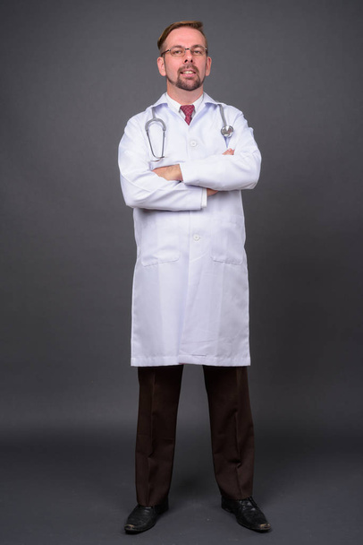 Biondo barbuto uomo medico con pizzetto contro sfondo grigio - Foto, immagini