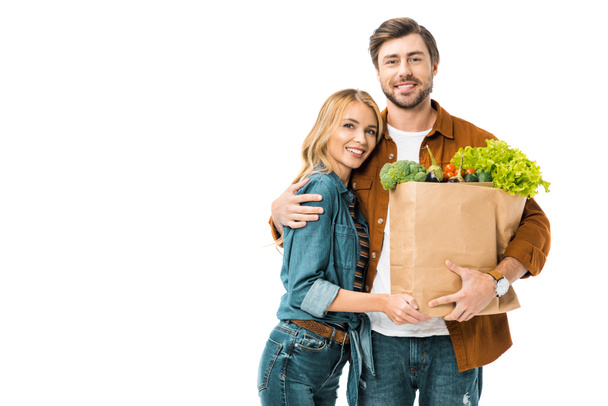 young man holding paper bags with products and embracing girlfriend isolated on white - Photo, Image