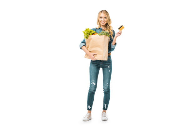 happy woman holding shopping bag with food and showing credit card isolated on white - Valokuva, kuva
