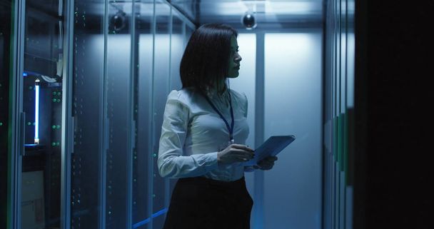 Técnico femenino trabaja en una tableta en un centro de datos
 - Foto, imagen