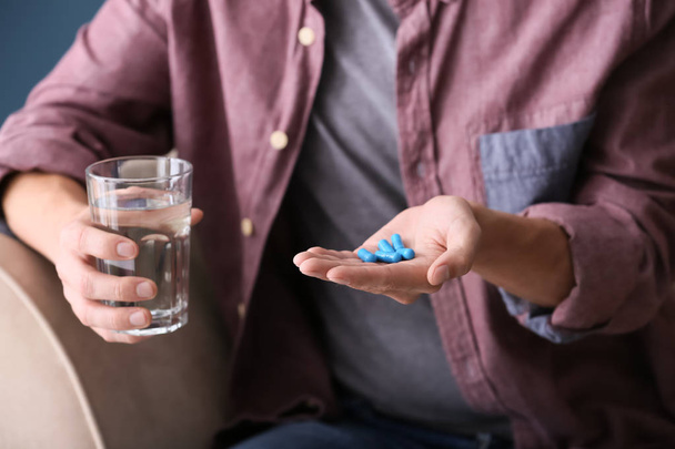 Man holding pills and glass of water, closeup - Foto, imagen