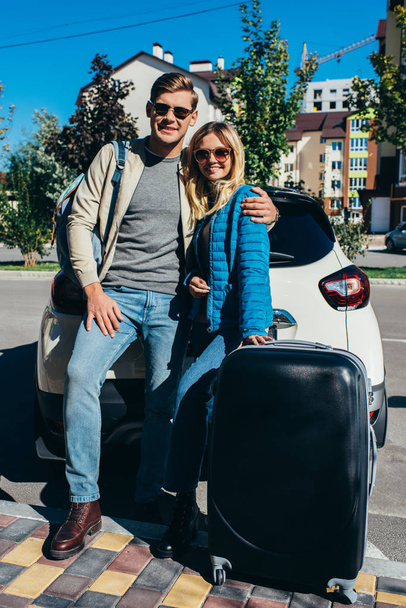 pár mosolygó turista a poggyász kocsi utca közelében - Fotó, kép
