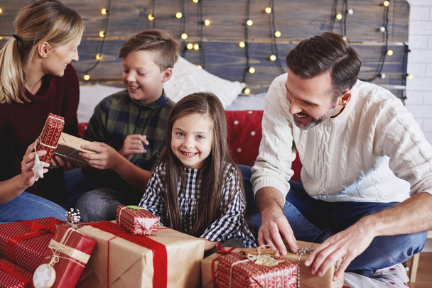 Niños felices abriendo regalo de Navidad con los padres
 - Foto, imagen