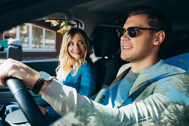 smiling woman at boyfriend driving car during vacation - 写真・画像