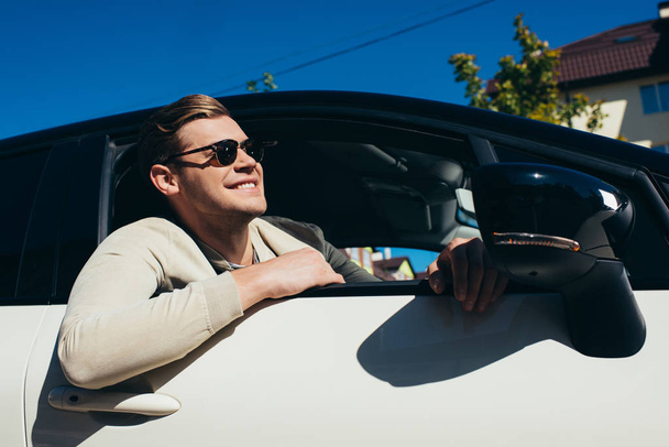 усміхнений молодий чоловік витягує вікно автомобіля за кермом автомобіля
 - Фото, зображення