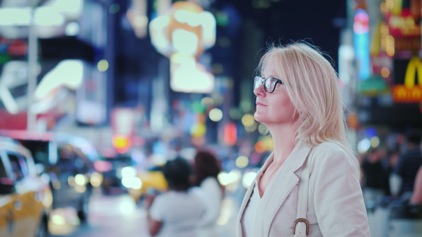 Aantrekkelijke vrouw bewondert de lichten van het beroemde Time Square in New York, gele taxi 's passeren - het symbool van de stad - Video