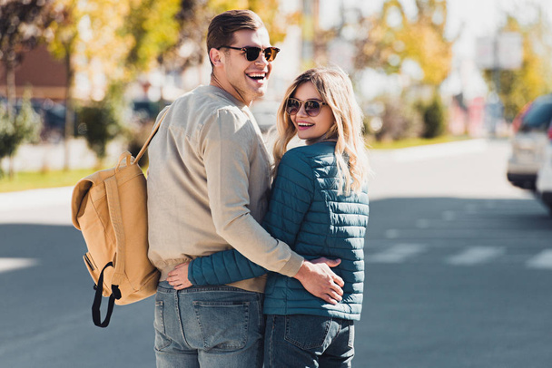visão traseira de abraços casal feliz enquanto caminhava na rua na nova cidade
 - Foto, Imagem