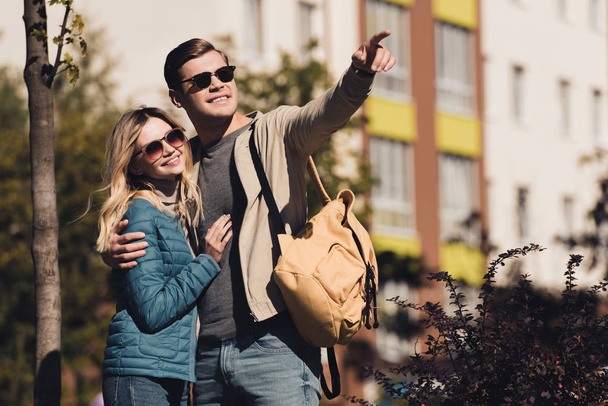 hombre mostrando algo a su novia mientras caminan juntos en nueva ciudad
 - Foto, Imagen