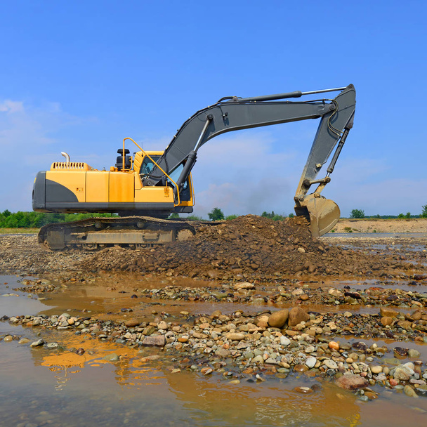 Extraction et chargement de gravier excavé dans le courant dominant de la rivière
 - Photo, image