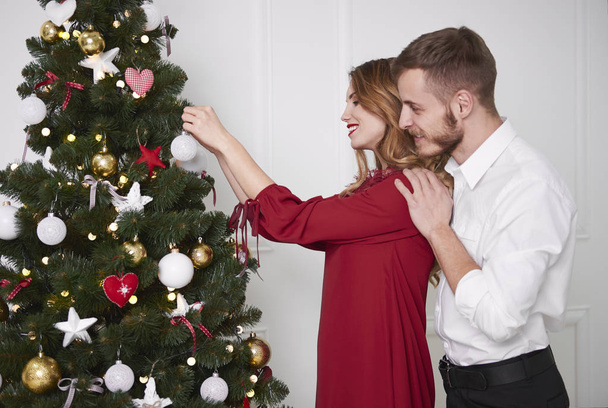 Elegant couple decorating the christmas tree  - Foto, afbeelding