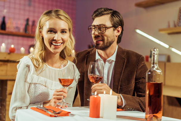 happy couple with wine glasses celebrating and having date at table with candles in restaurant  - Foto, immagini